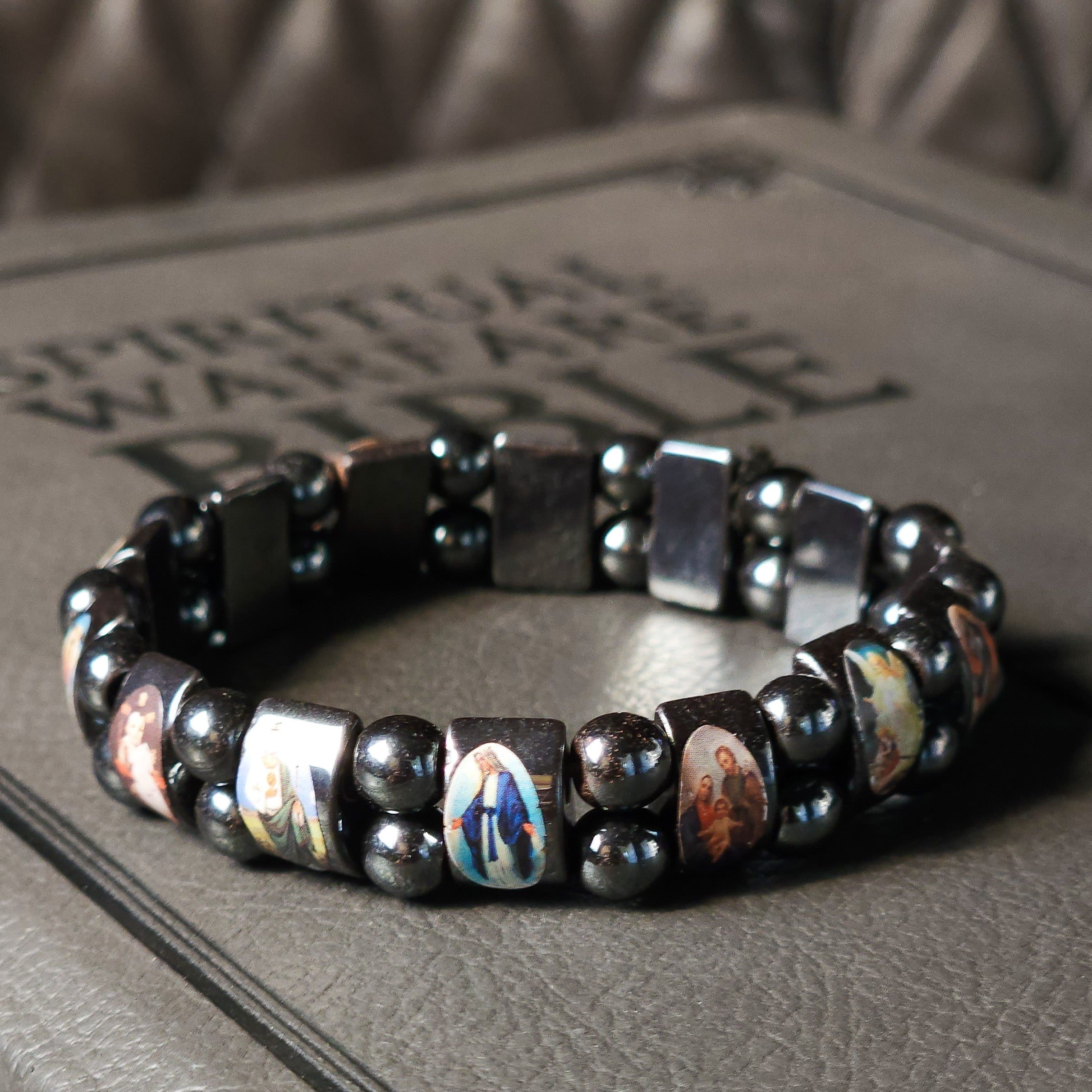Catholic Saints Bracelet with Hematite Stones on top of a Spiritual Warfare Bible.